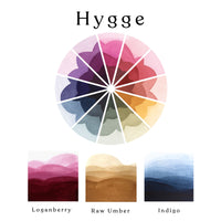 A colour wheel of the Hygge watercolour set and ombre swatches of Loganberry, Raw Umber and Indigo watercolour paints.