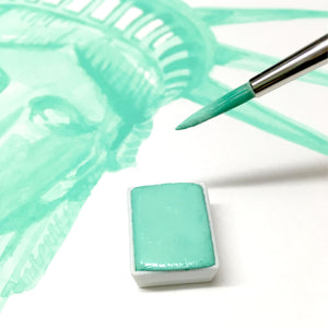section watercolour painting of statue of Liberty with a pale green watercolour paint and the end of a paintbrush