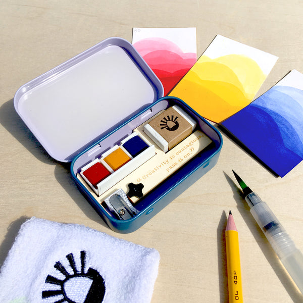 The sketching tin in use, with red yellow and blue watercolour paints and swatches.