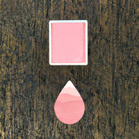 Blush watercolour half pan above a droplet shaped ombre swatch in Blush watercolour paint, on a rustic dark wooden background.